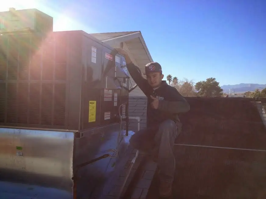 HVAC technician performing Heat Pump Repair on a rooftop unit in Durham