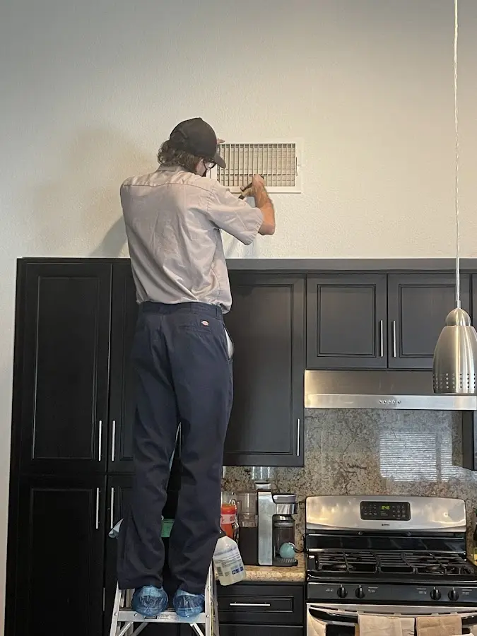 Technician inspecting an air vent during HVAC service in Durham